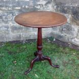 A mahogany tilt top occasional table, the circular top raised on a turned column to three outswept