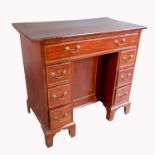 A Georgian style kneehole writing desk, having a frieze drawer flanked by three short drawers around