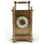 A brass cased carriage clock, the decorated case with fluted columns and scrolls, having an enamel