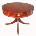 A circular mahogany drum table, in the Regency style with a tooled leather top, fitted with cross