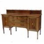 An Edwardian bow front sideboard, having a galleried top over a central panel flanked by doors, over