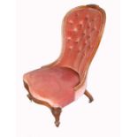 A Victorian Grandmothers Chair, with Button back upholstery, carved foliate decoration and raised on