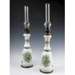 A pair of late 19th century milk glass oil lamps, decorated with flowers, converted to