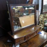 A 19th century mahogany swing frame toilet mirror, raised on a bow front base, with three drawers,