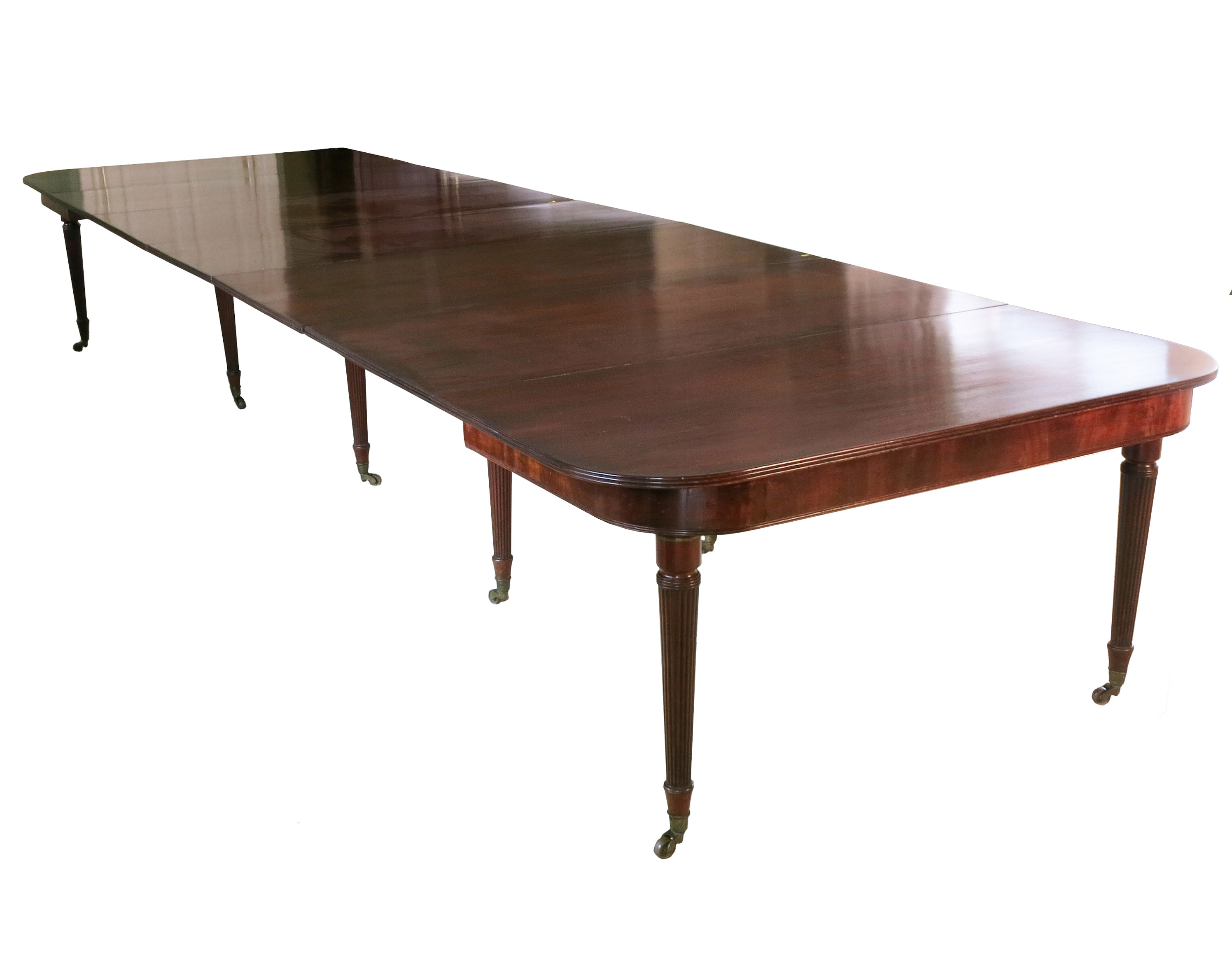 A Regency mahogany extending dining table, in the manner of Gillows, raised on ten reeded tapering