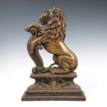 A Victorian gilded metal door stop, formed as a rampant lion and scrolls, on a stepped base,