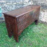 An Antique oak coffer, with rising lid, and carving to the front, raised on style feet, width 42.