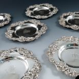 Seven American Sterling silver coasters, having a fruit and flower cast border, the centres engraved