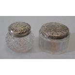 Two silver topped glass dressing table pots decorated with putti