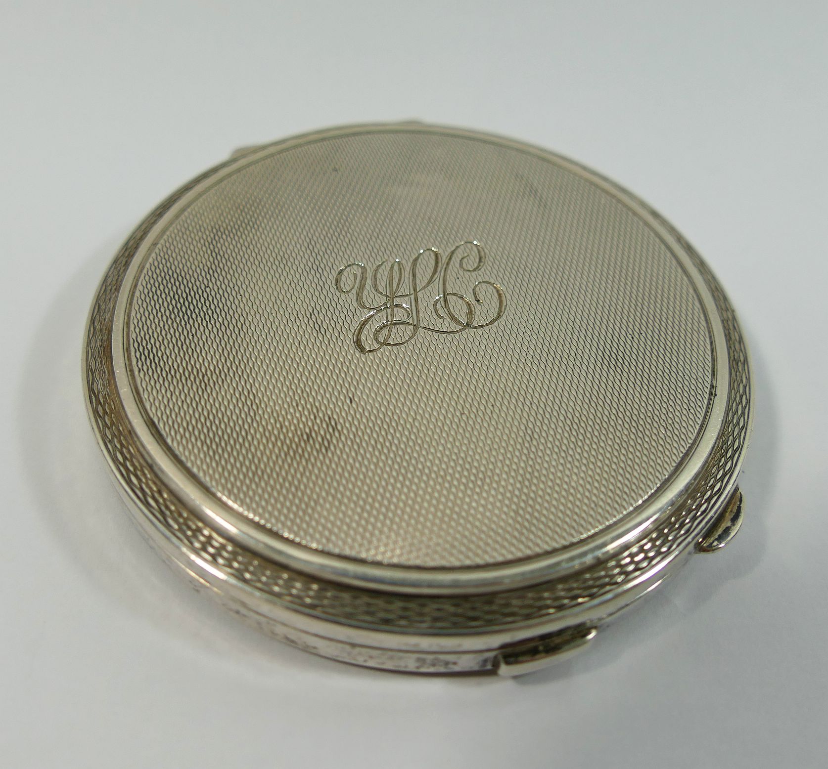 A silver circular compact, Birmingham 1960, with engine turned deocration, 7.8cm diameter, 3.