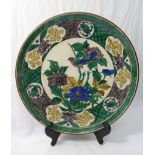 A Japanese porcelain charger, decorated in green, yellow, blue and grey with double boarder,