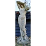 A reconstituted stone figure of a maiden with clinging dress and her head in her arm,