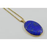 A 9 carat gold lapis lazuli oval pendant, London 1977, 4cm x 3cm, on yellow metal chain,