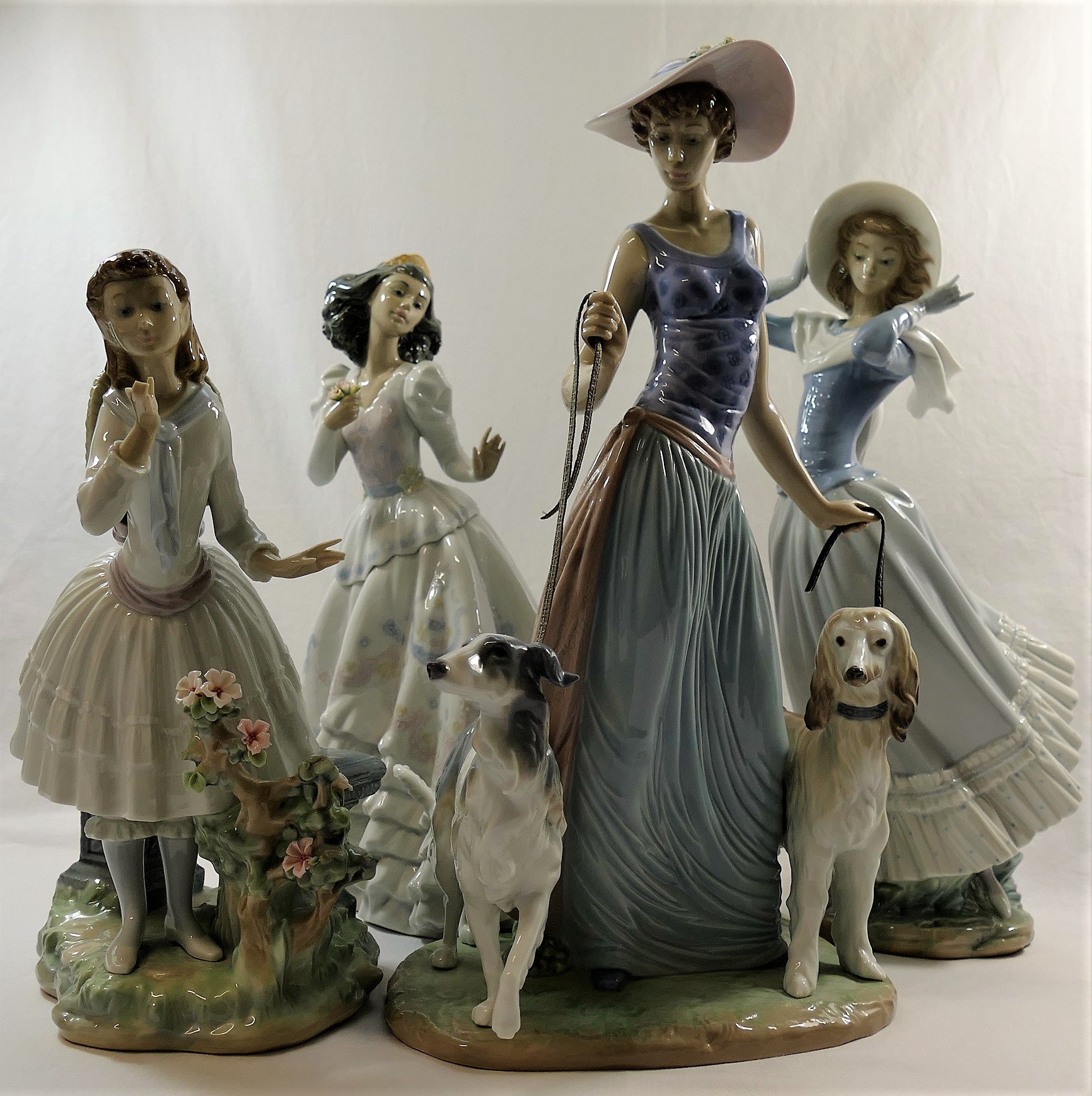 Four Lladro figures of ladies, the tallest walking two dogs,