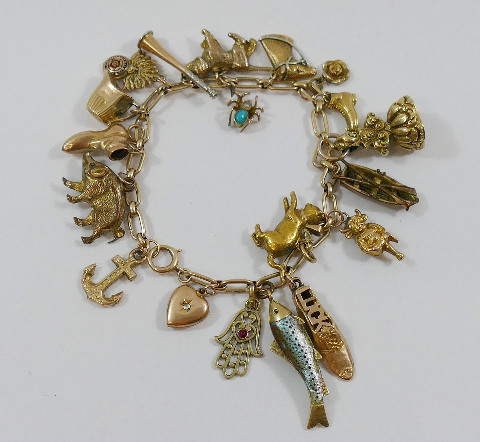 A yellow metal charm bracelet with 19 charms, seven hallmarked or stamped '9CT',