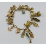 A yellow metal charm bracelet with 19 charms, seven hallmarked or stamped '9CT',