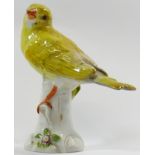 A porcelain figure of a yellow canary, perched on a tree stump,