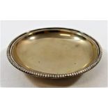 A small silver coloured metal circular dish, with beaded rim and raised on circular foot,