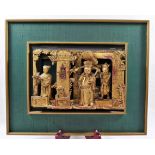 A framed Chinese carved gilt wood panel, of three figures within an interior, 16.5cm x 23.