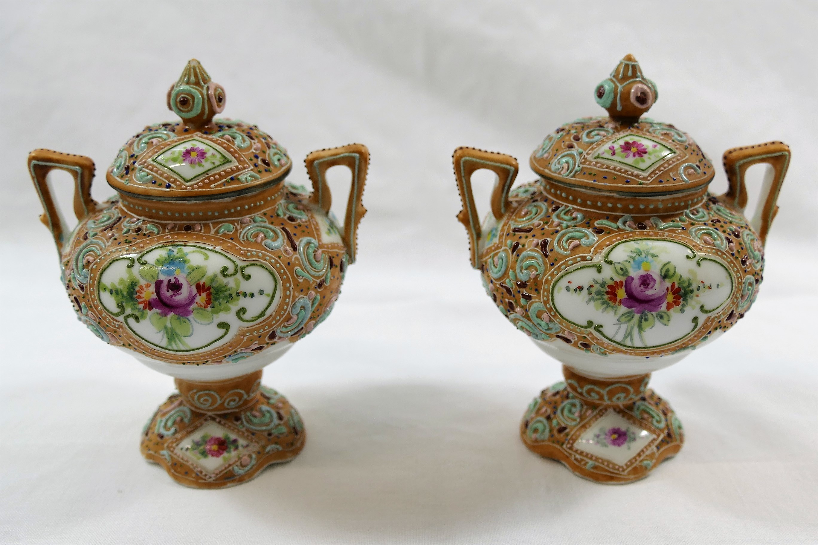 A pair of small Noritake two-handled lidded vases, hand painted with floral panels, 11.