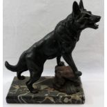 A patinated spelter figure of a German Shepherd standing with his front feet on a rock,