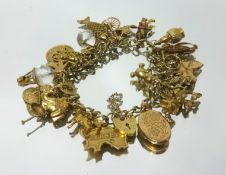 A 9ct gold charm bracelet with padlock clasp and safety chain, consisting of thirty two 9ct gold