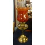 An oil lamp, with brass base, red shade and funnel, maximum height 52cm.