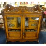 An early 20th oak smokers cabinet having two glazed doors with a fitted interior.