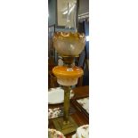An oil lamp with Corinthian column base, glass reservoir and orange shade with funnel, maximum