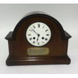 An Edwardian mantel clock in a mahogany inlaid case with presentation plaque to 'D.Hirst'.