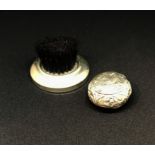 A silver and embossed round pill box and a silver finger brush (2).