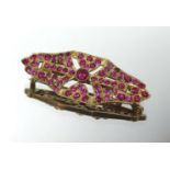 A yellow metal and ruby style brooch, unmarked.