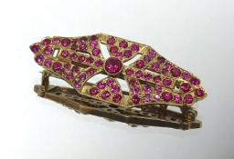 A yellow metal and ruby style brooch, unmarked.