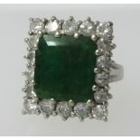 An 18ct white gold ring set with a large square cur emerald within a diamond border, finger size L/
