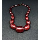 A red amber necklace of graduated beads, the largest approx 24mm diameter, weight 70gms.
