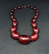 A red amber necklace of graduated beads, the largest approx 24mm diameter, weight 70gms.