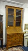 An antique English walnut bureau bookcase the upper section with two glazed doors, enclosing two