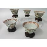 A set of five Chinese porcelain tea bowls (one damaged) with carved wood stands, diameter 9.5cm.