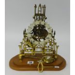 A Skeleton clock with key pendulum mounted on a wood base, height 31cm.