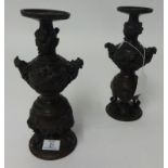 A pair of oriental bronze candlesticks richly decorated with dragons, height 22cm.