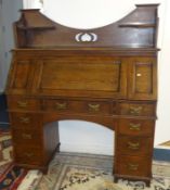 An oak arts and crafts style desk with carved three quarter gallery, full front and fitted