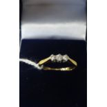 An 18ct and platinum small diamond set three stone ring, finger size L.