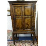 An antique English joined oak cupboard on stand with single moulded panel door, enclosing two shaped