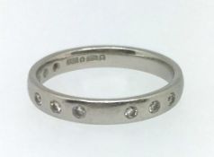 A platinum wedding band set with nine small diamonds, approx 4.5gms, ring size M.