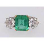 A platinum, emerald and diamond three stone ring, the centre stone measuring approx 9mm x 7mm, the