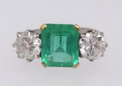 A platinum, emerald and diamond three stone ring, the centre stone measuring approx 9mm x 7mm, the