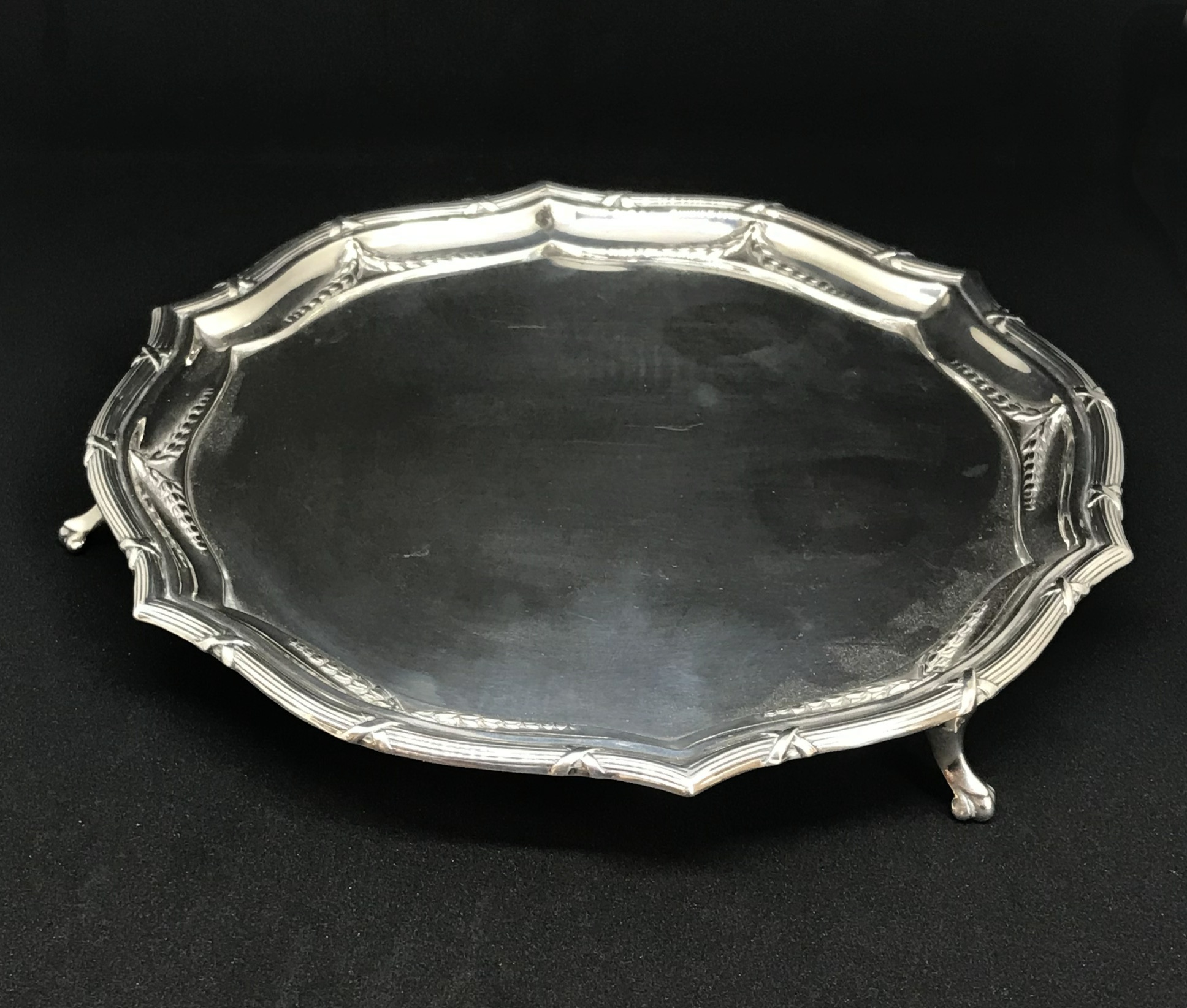 A Geo V sterling silver salver with paw feet and a ribbon and bow leaf design border, makers mark 'G