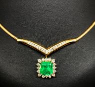 A fine emerald and diamond cluster drop pendant set in 18ct yellow gold attached to a herringbone