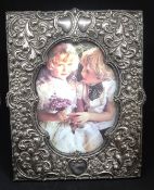 A late Victorian silver photo frame by Walker & Hall, richly decorated, 20.50cm x 16cm.