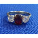 A 18ct three stone engagement ring set with an oval faceted cut ruby and two brilliant cut diamonds,